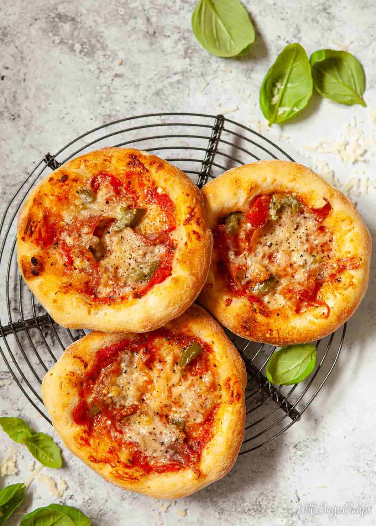 Mini Pizzas on a wire rack with prosciutto and chilli topping.