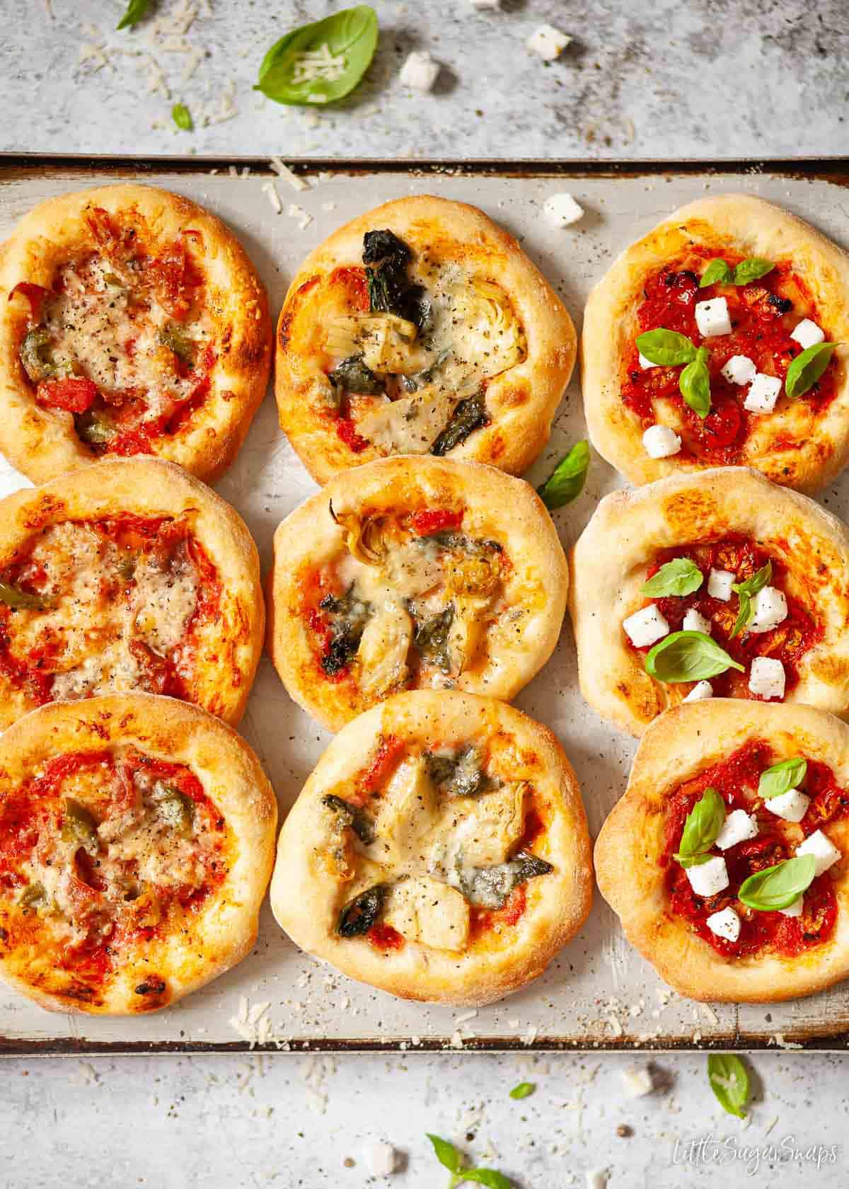 Assorted mini pizzas on a baking tray.