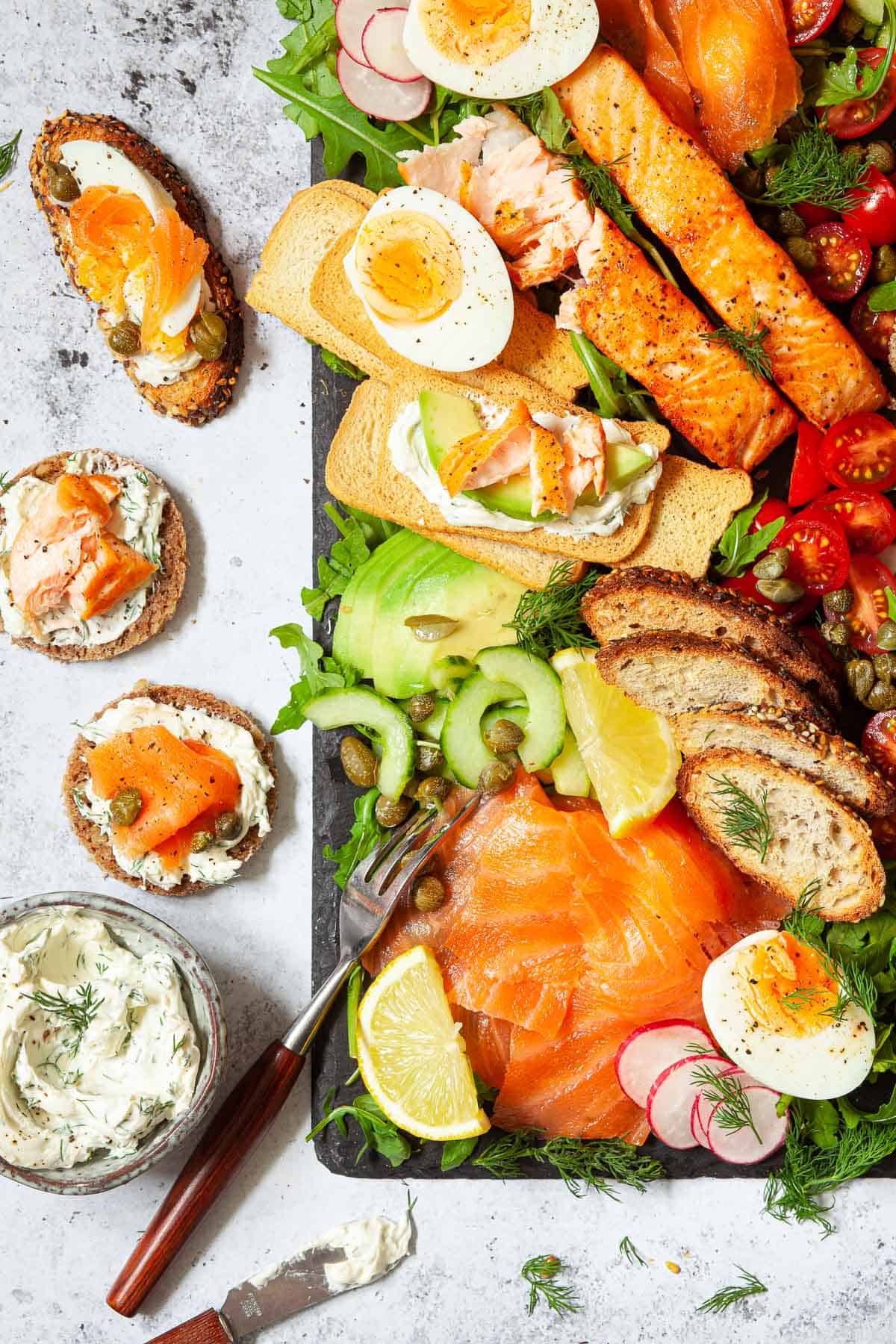 A salmon platter with assembled toasts at the side made from ingredients from the platter