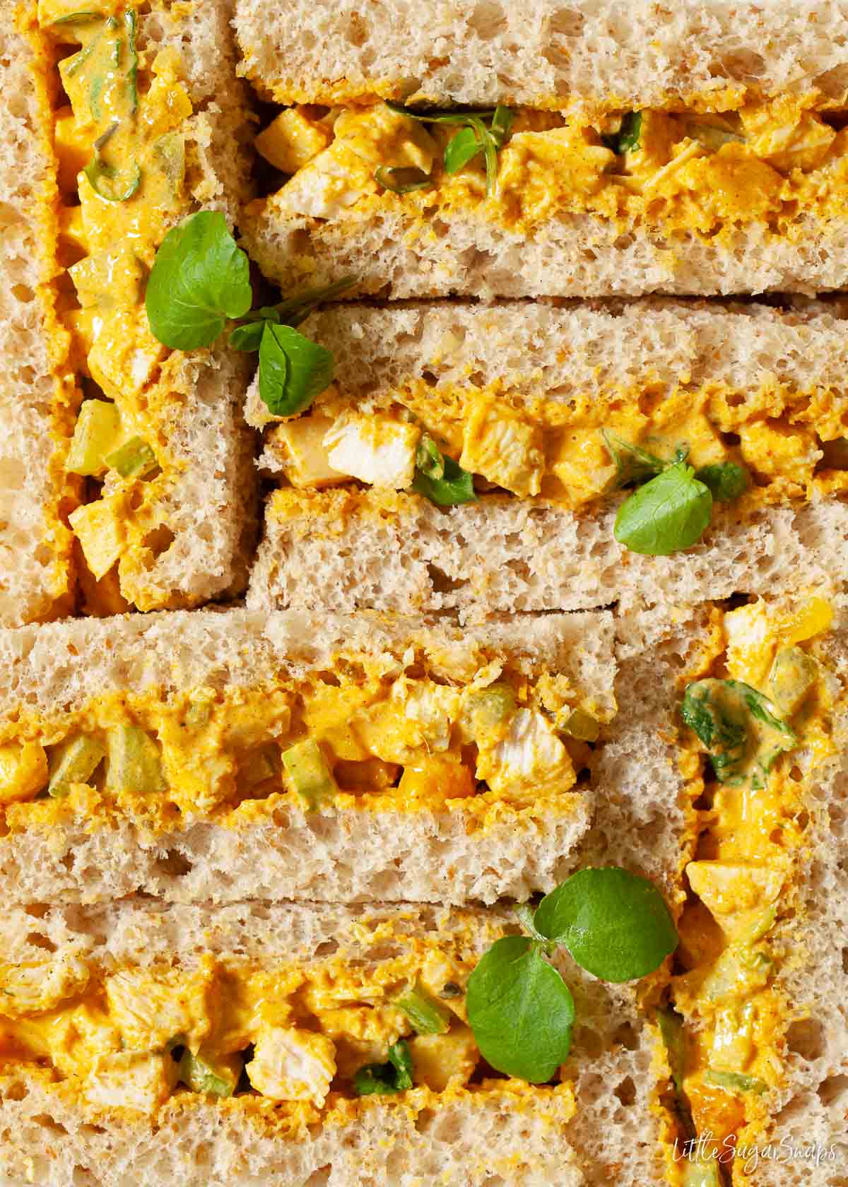 Close up of Coronation Chicken Sandwiches on brown bread with watercress garnish