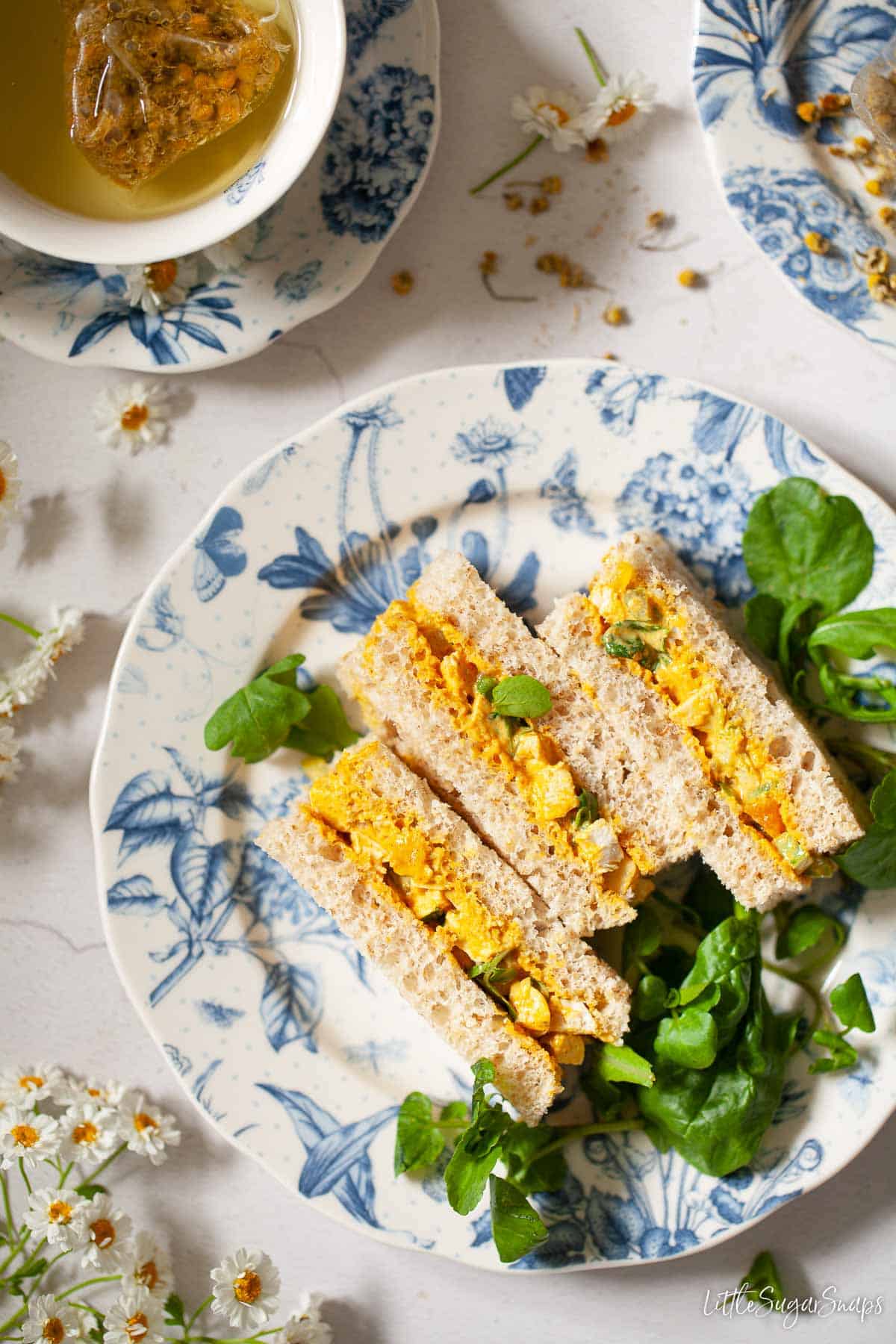 Three dainty sandwiches on a plate as part of afternoon tea