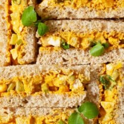 Close up of Coronation Chicken Sandwiches on brown bread with watercress garnish