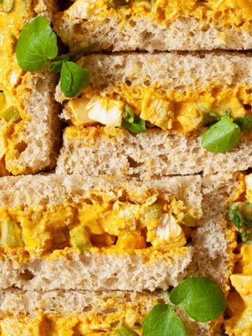Close up of Coronation Chicken Sandwiches on brown bread with watercress garnish