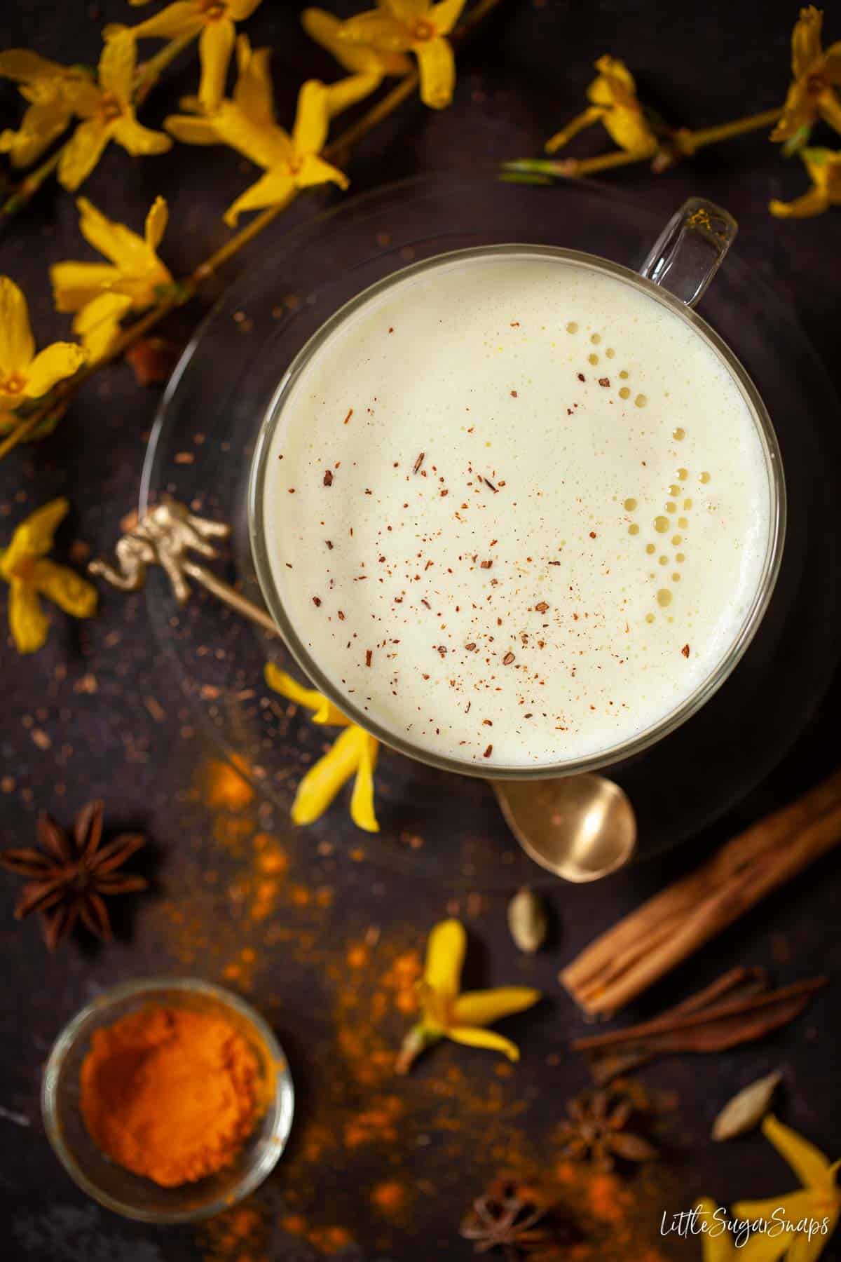 Overhead view of golden turmeric latte with a frothy top and dusting of cinnamon