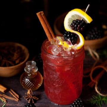 A blackberry bramble garnished with lemon and fresh fruit