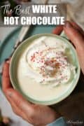 Hands holding a mug of white hot chocolate with text overlay