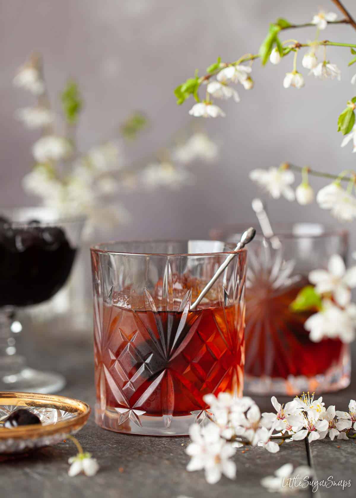 An amaro averna cocktail with dark cherries as a garnish.