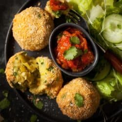 Close up of smoked haddock fish cakes with tomato relish and side salad.
