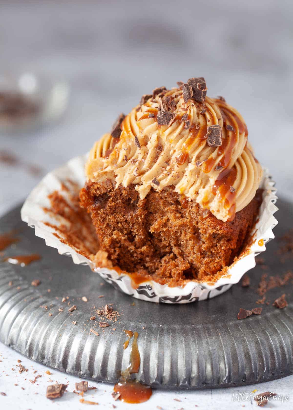 A part eaten coffee cupcake with coffee buttercream and coffee caramel drizzle.