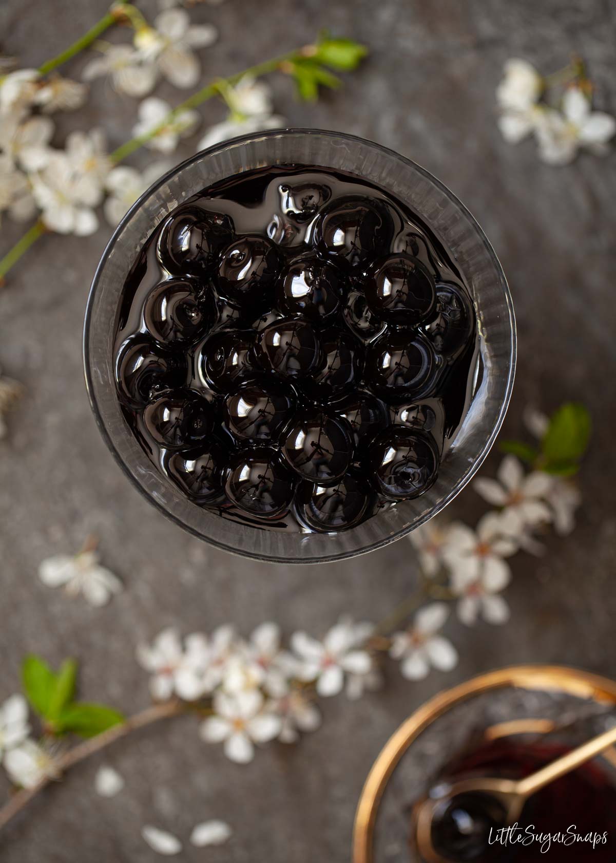 A bowl of dark coloured maraschino cocktail cherries in syrup.