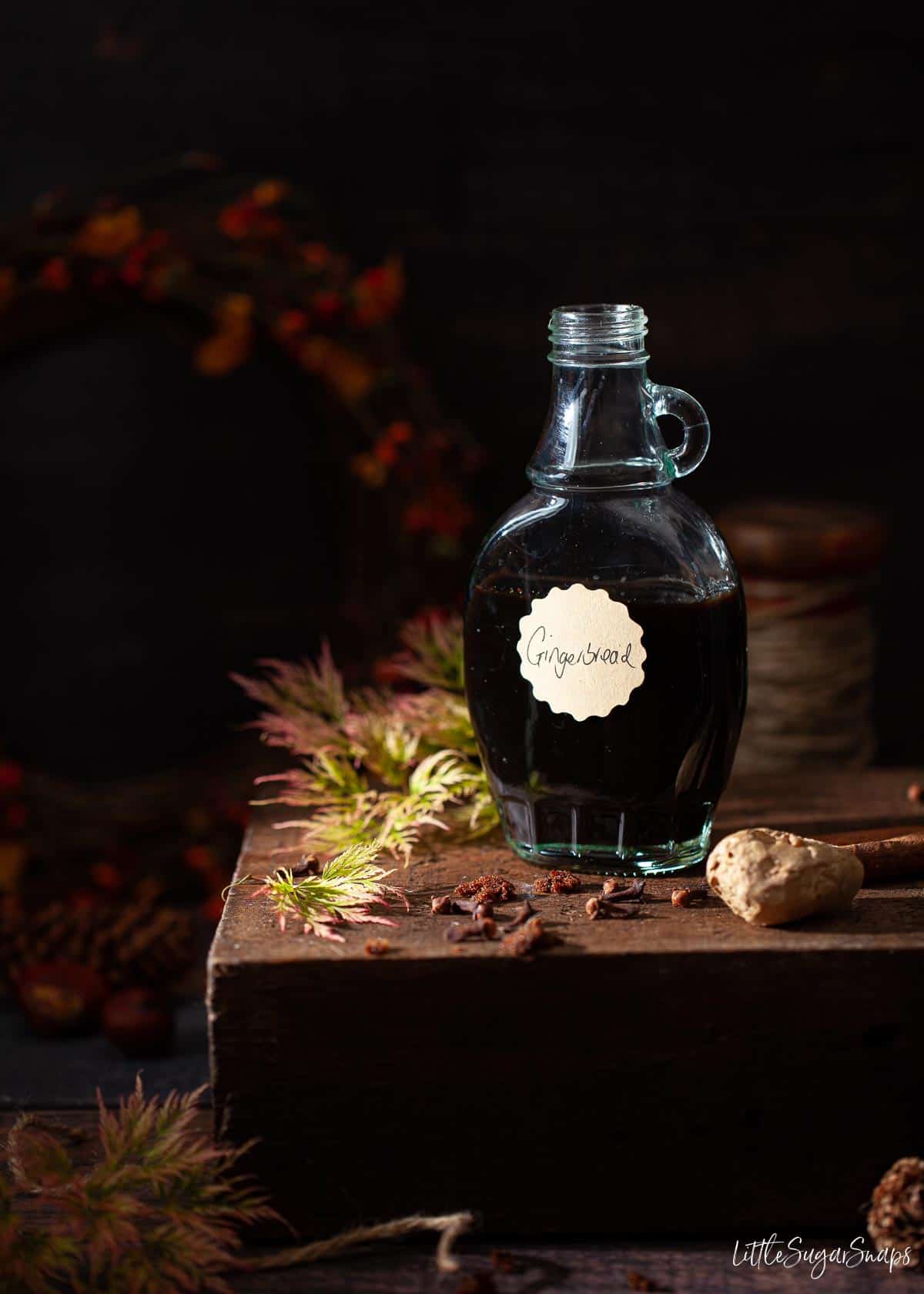 A bottle of homemade gingerbread syrup with autumn foliage in the image.