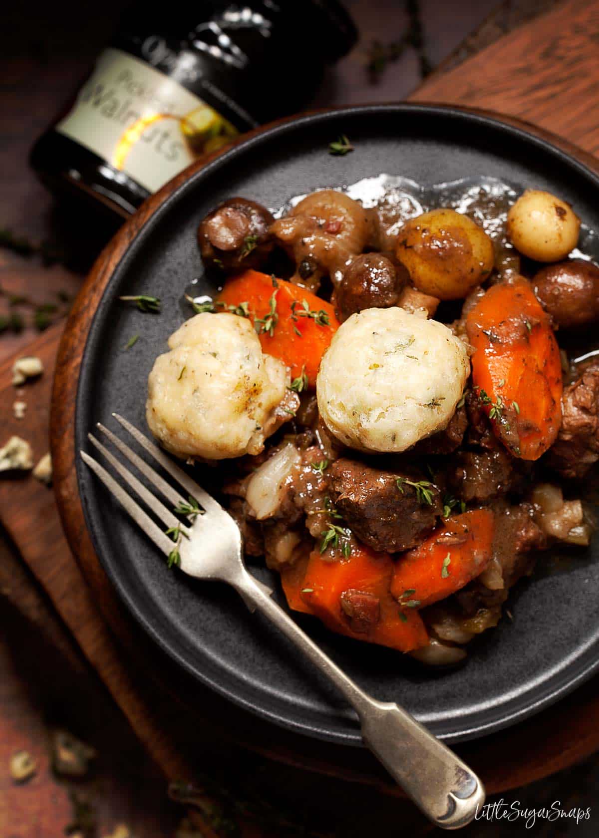 Overhead view of a serving of slow cooked beef and dumplings on a plate.