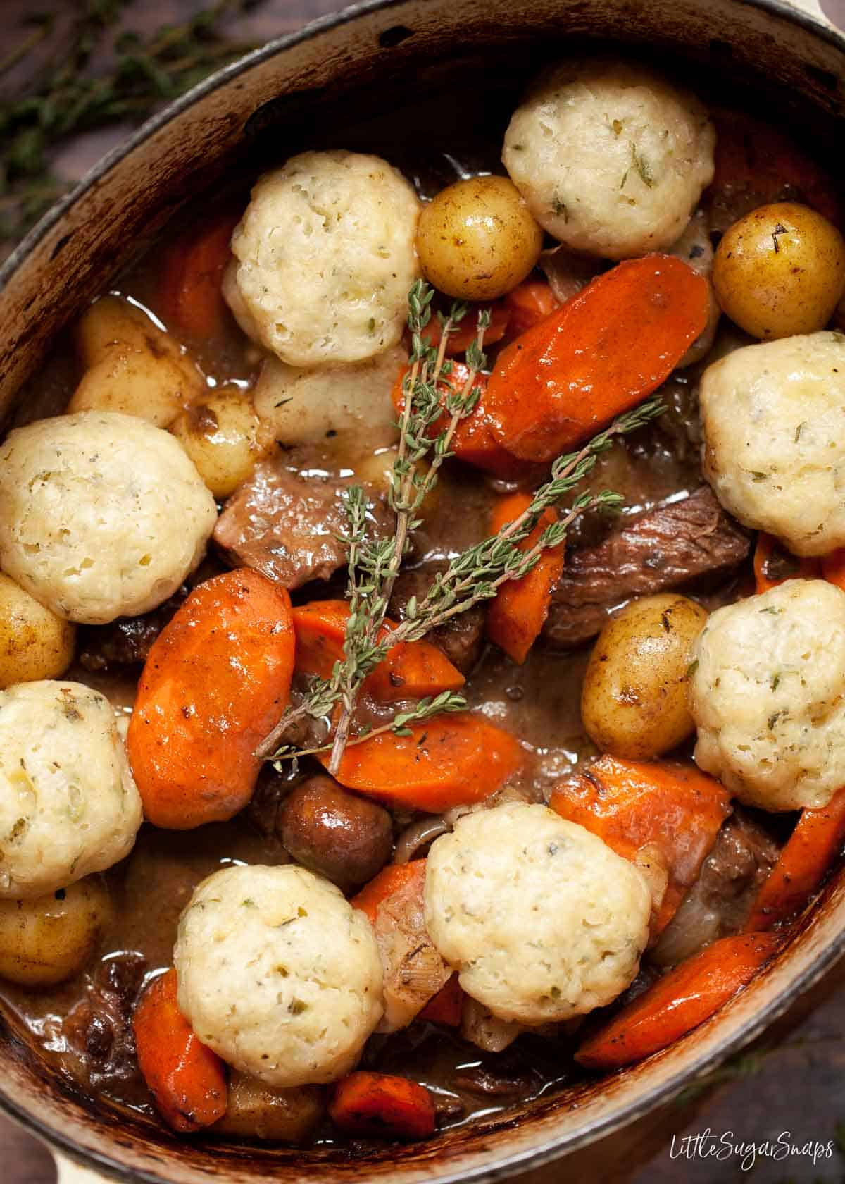 A cast iron pot full of slow cooked beef stew and dumplings.