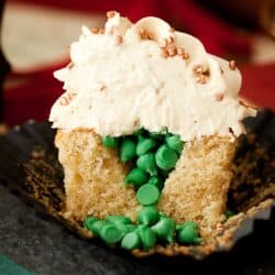 A cut into cupcake revealing green candy drops inside