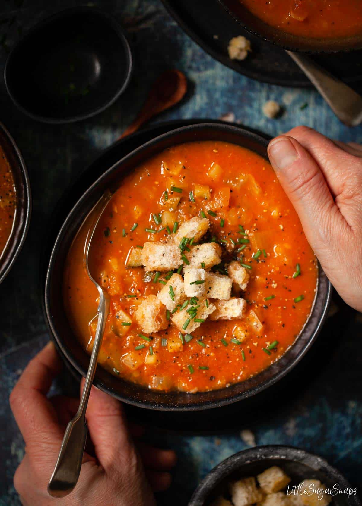 Person about to start eating tomato and fennel soup from a bowl.