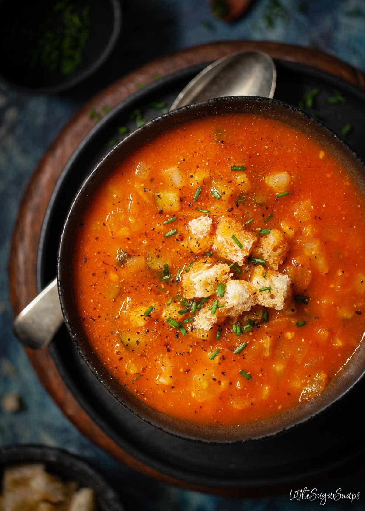 Tomato and fennel soup in a bowl topped with croutons.