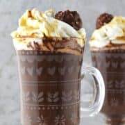 A rich hot chocolate drink with whipped cream in a patterned glass.