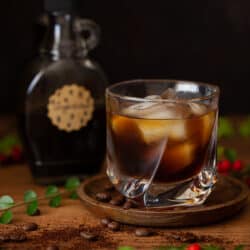 Close up of a Black Russian Gingerbread Cocktail with syrup behind.