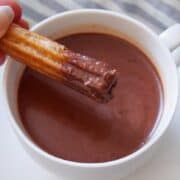 Churros being dipped into Spanish hot chocolate.