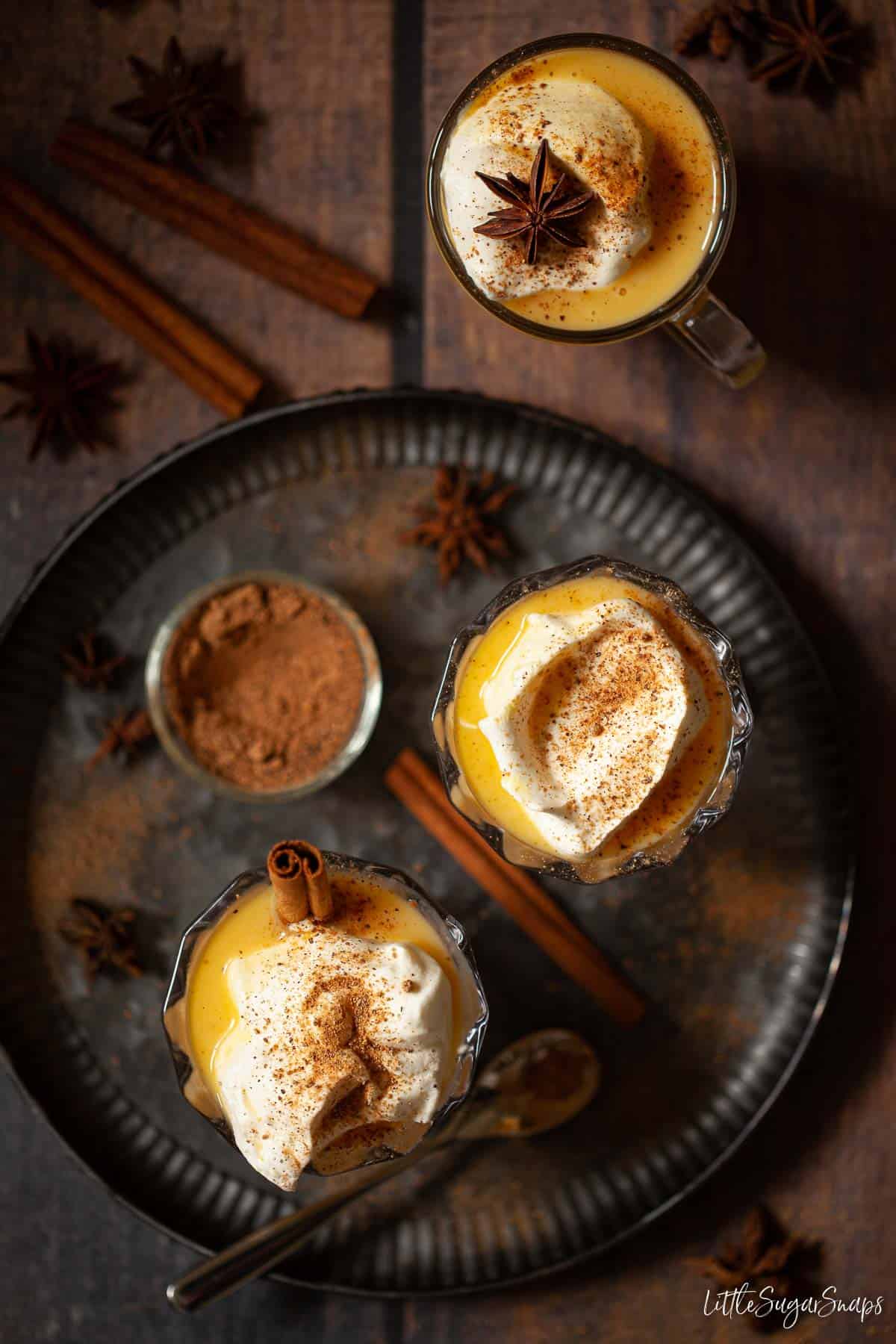 Three advocaat drinks topped with cream and spices.