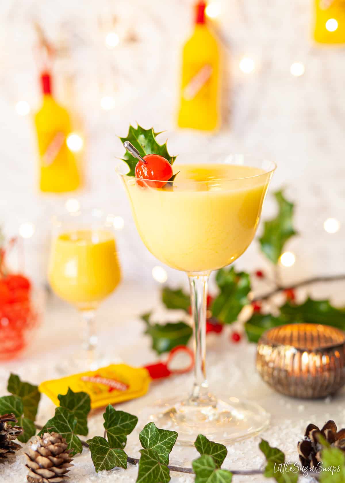 An advocaat snowball cocktail garnished with holly and a cherry.