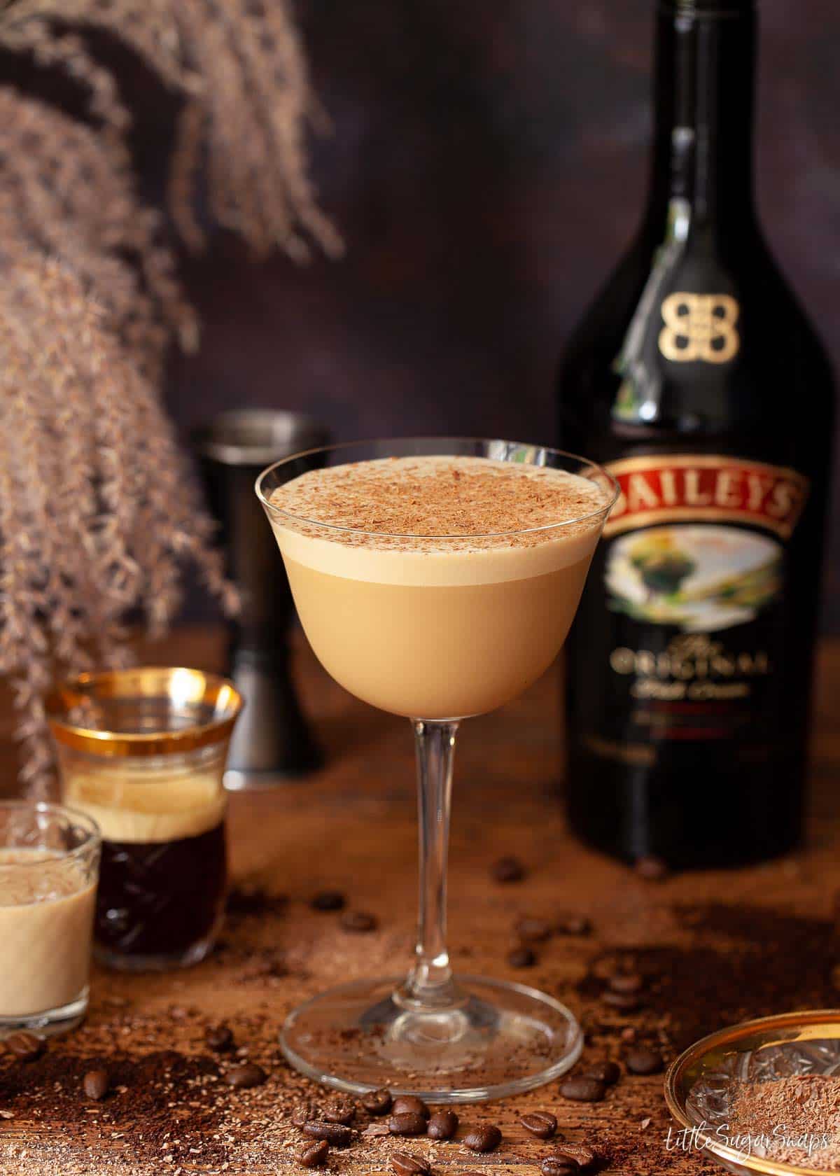 A Baileys espresso martini with glasses of coffee and Irish Cream at the side.