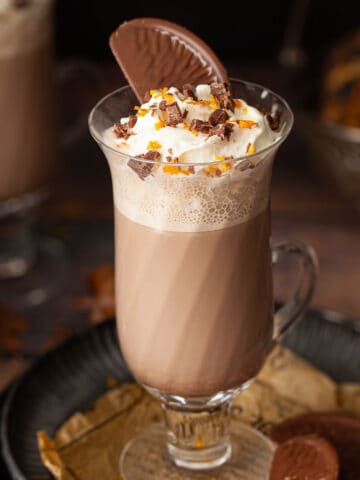 A hot chocolate topped with cream and a Terry's Chocolate Orange Segment.
