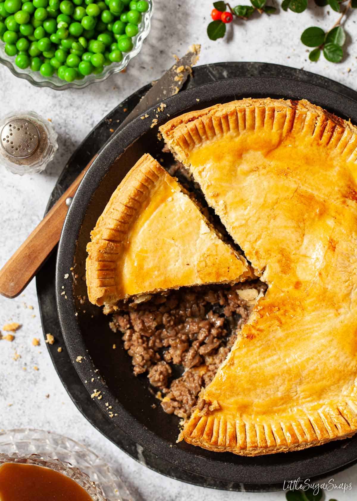 Mince and onion savoury pie with a slice removed.