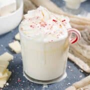 A milky drink topped with cream and candy cane chunks.