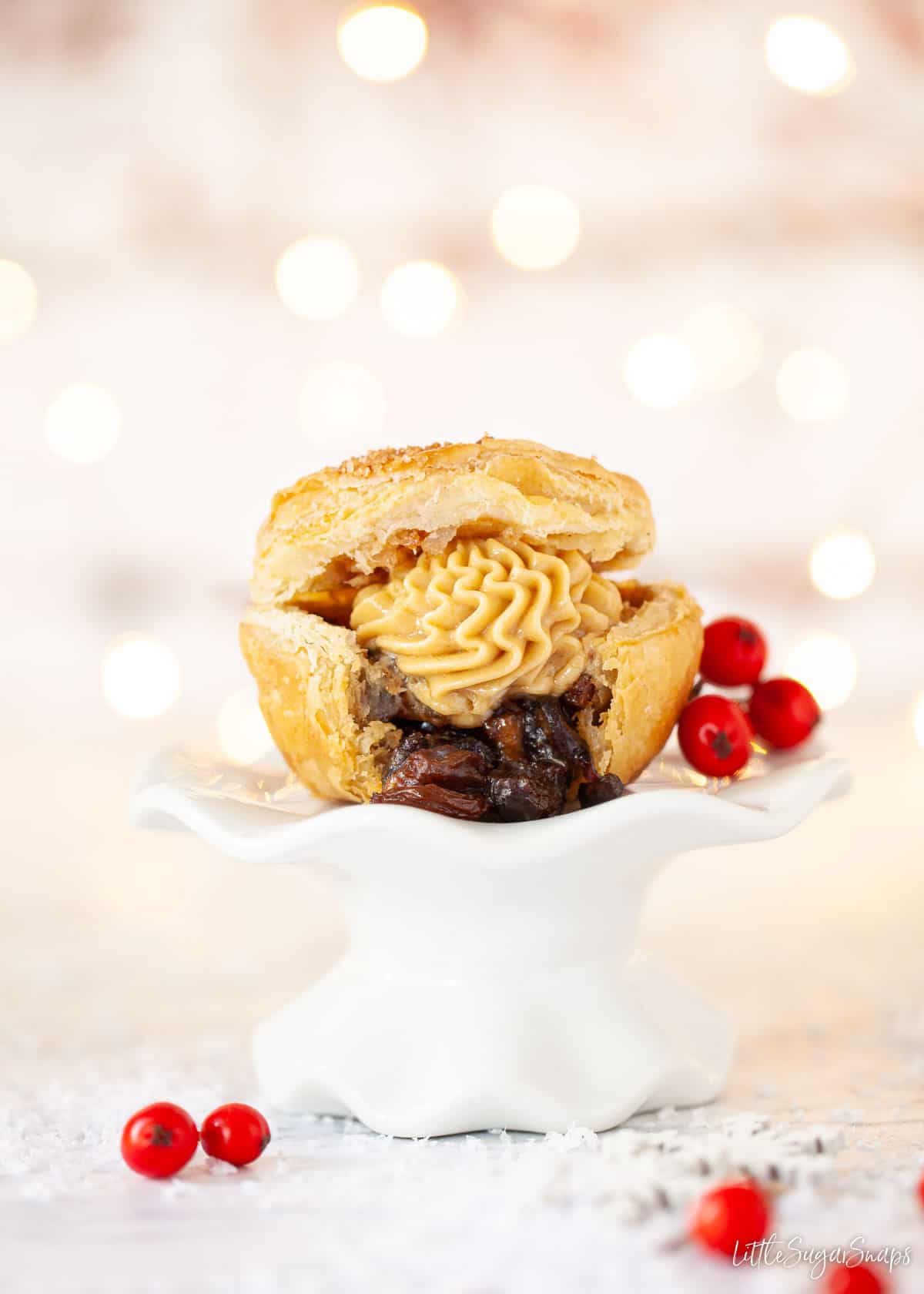 A cut open mince pie served with advocaat butter on a small stand.