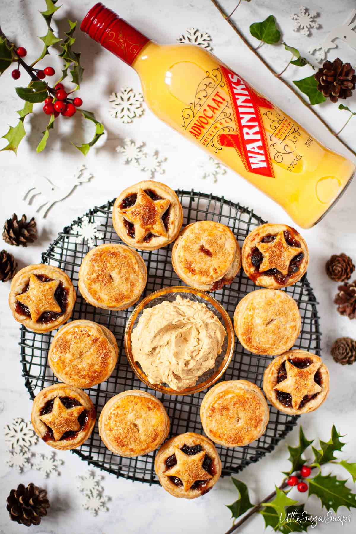 Overhead view of festive fruit mince tarts with a bottle of advocaat in shot.