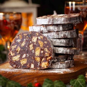 Slices of chocolate salami sausage stacked up on a wooden board.