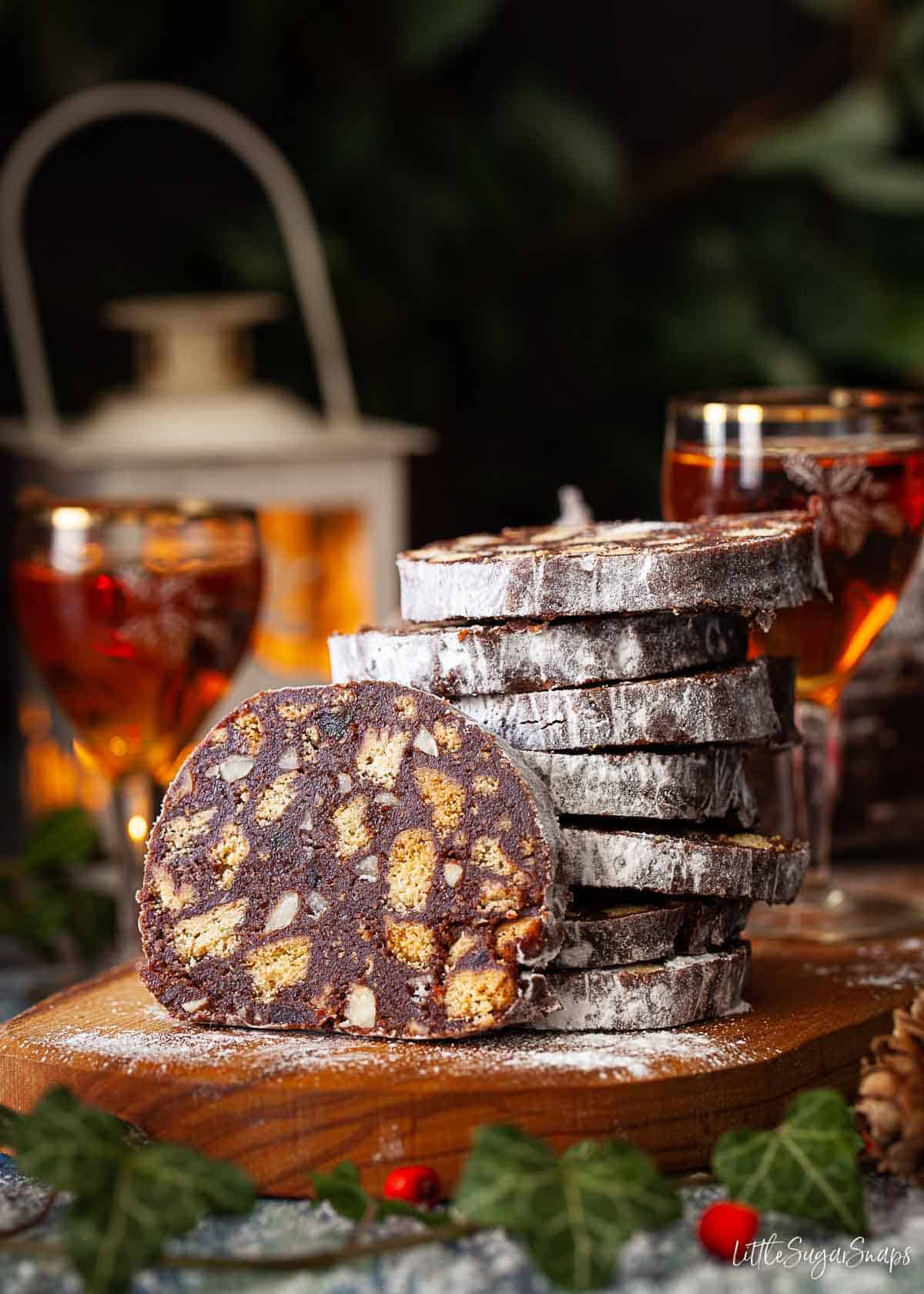 Slices of chocolate salami stacked up on a wooden board.