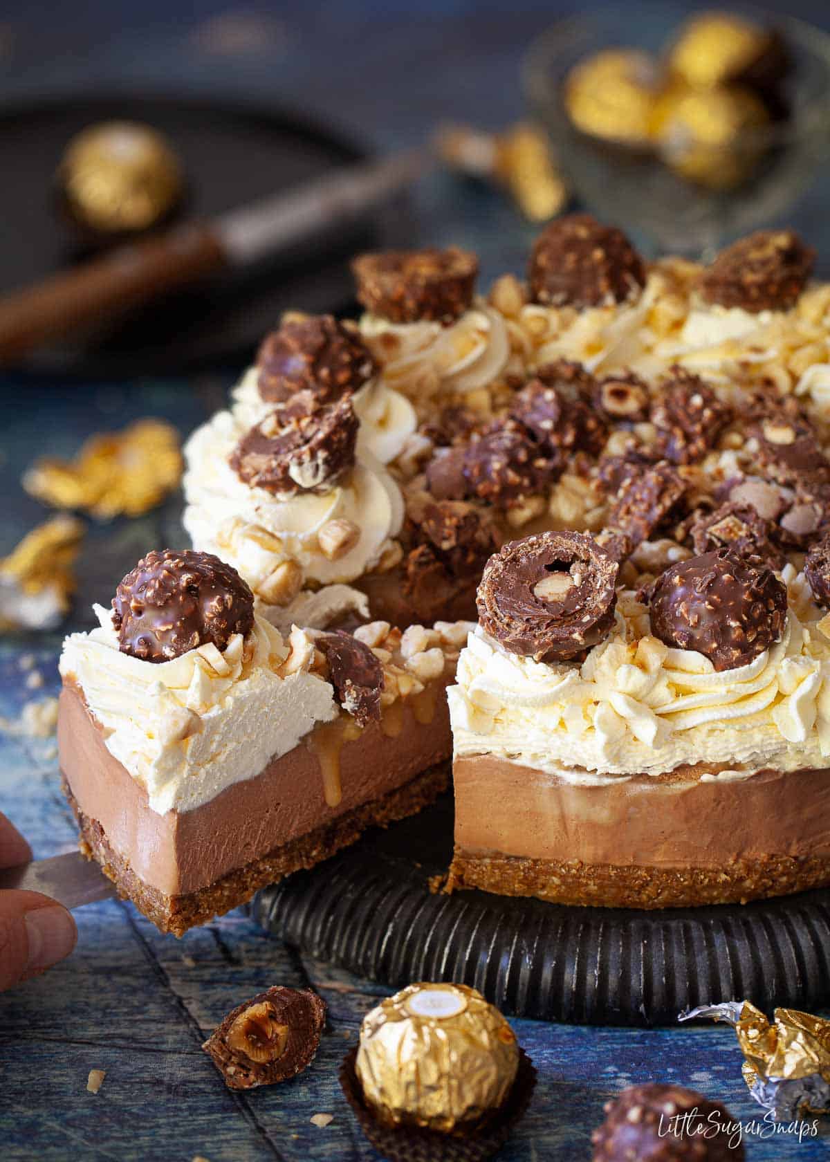 Person serving a slice of Ferrero Rocher Cheesecake.