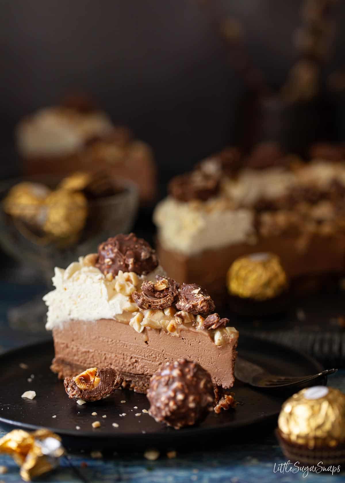 A slice of chocolate and hazelnut Ferrero Rocher Cheesecake on a plate.