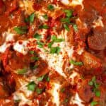 Close up of slow-cooked goulash with soured cream and parsley garnish.