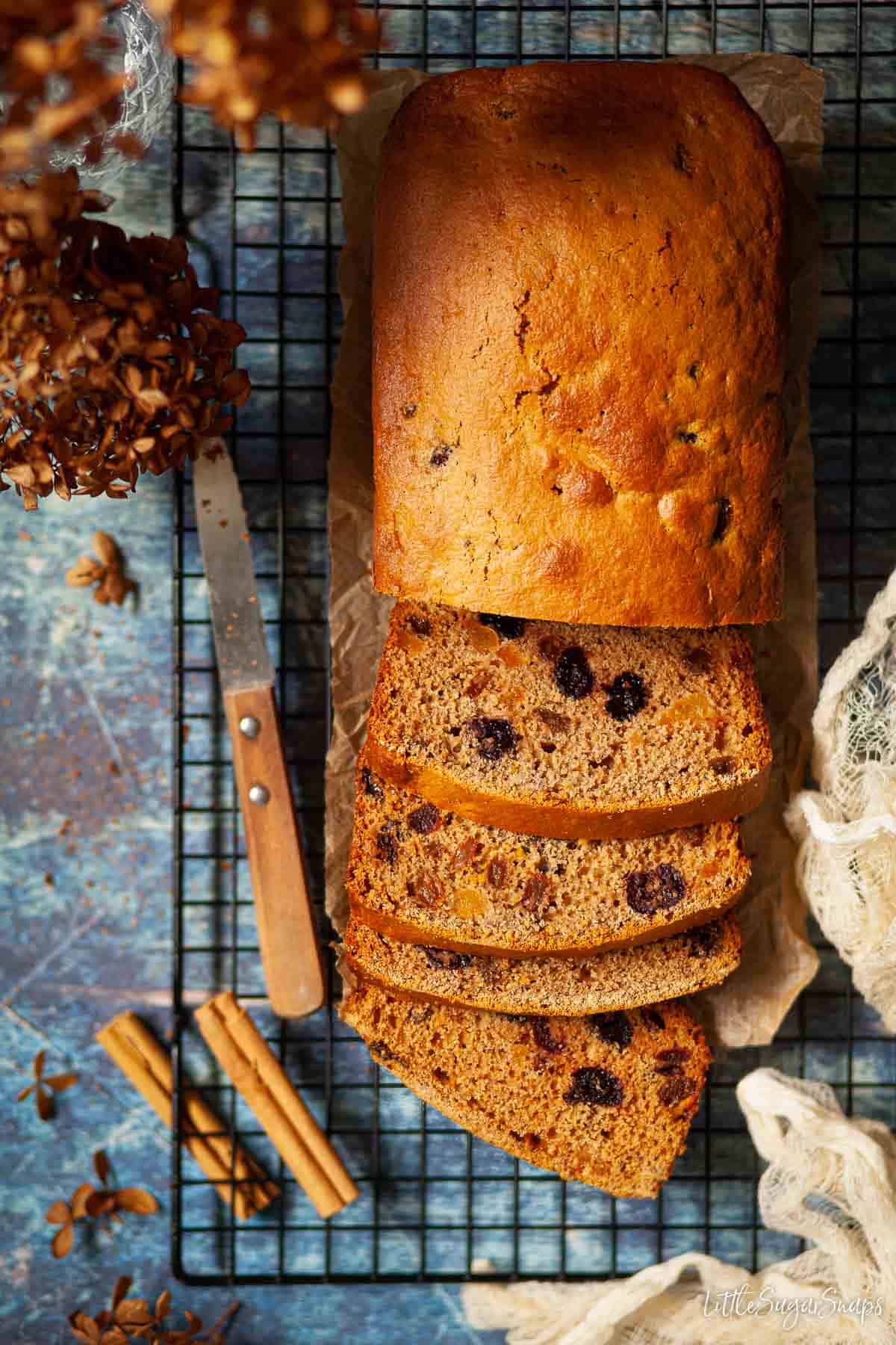 Overhead view of cinnamon and cherry tea bread cake partially sliced.