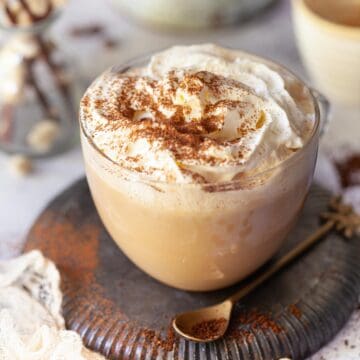 Glass mug of white chocolate mocha coffee with whipped cream and cocoa powder.