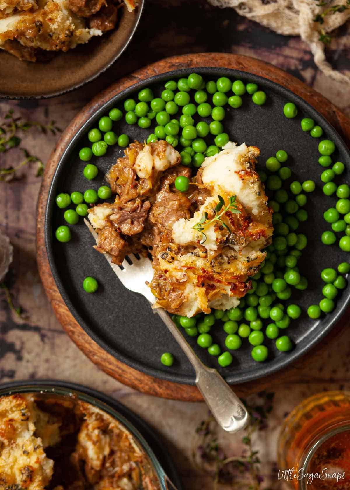 Steak and Stilton pie served on a plate with peas.