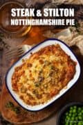 An enamel dish holding potato topped steak and stilton pie with text overlay.