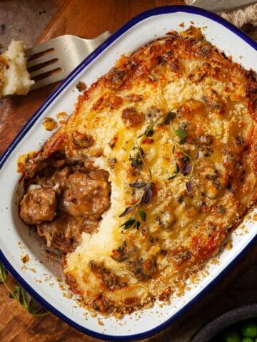 A part eaten steak and stilton pie in an enamel pot.