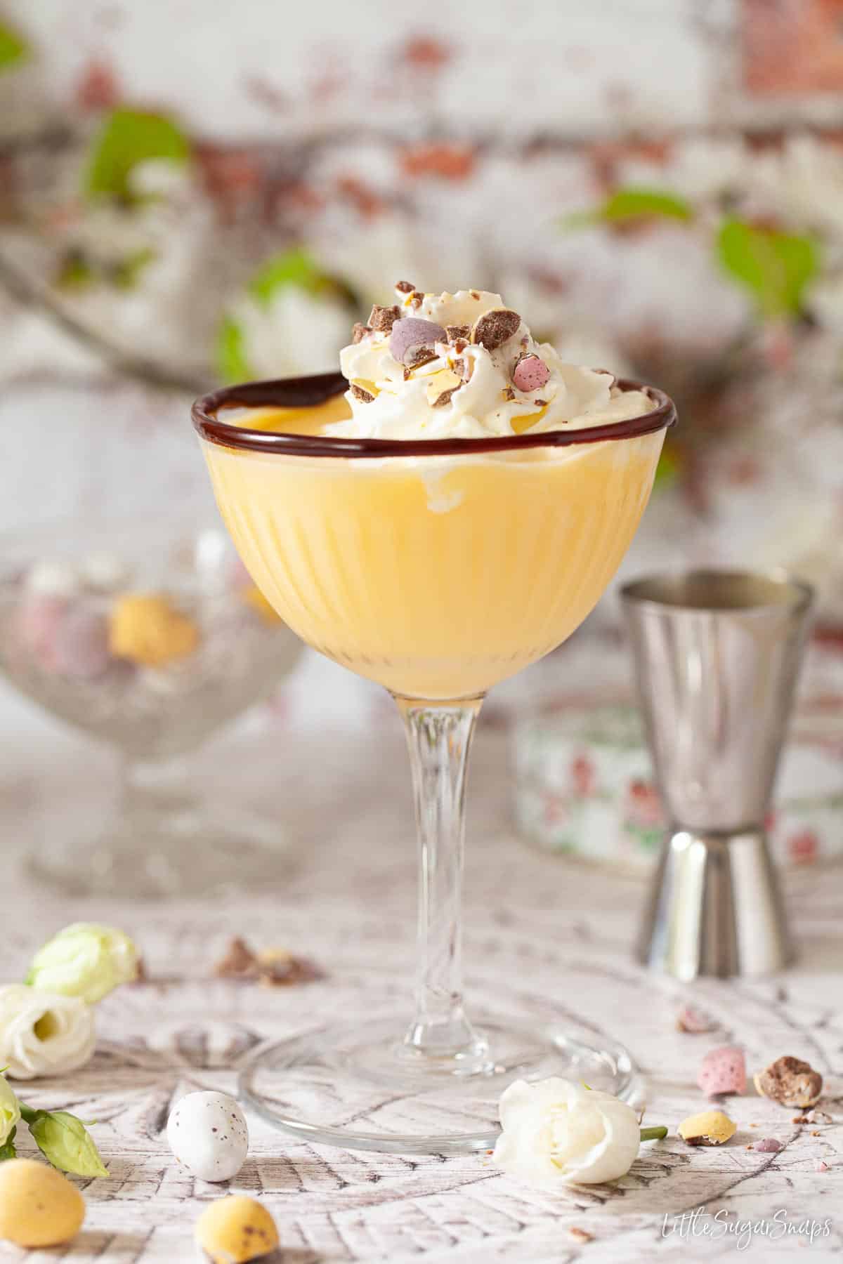 An advocaat Easter cocktail decorated with whipped cream and crushed candy eggs.