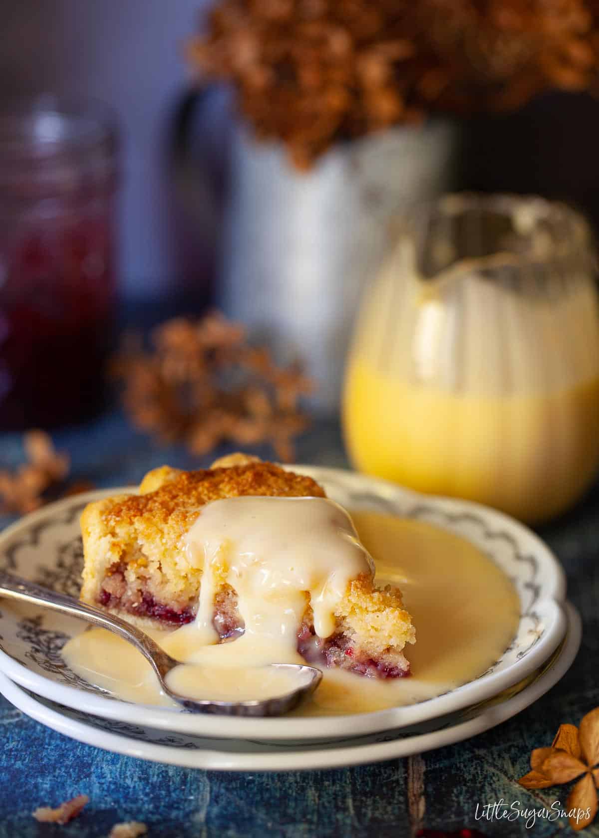 A slice of Buxton pudding with custard drizzled over it.