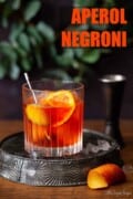 Negroni made with Aperol Bitters and garnished with olives and a slice of orange with text overlay.