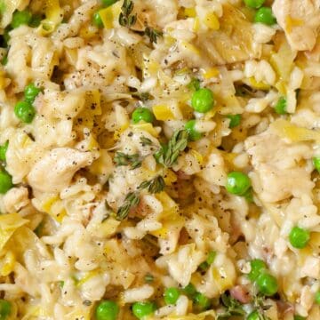 Close-up view of creamy risotto rice with leeks, chicken, bacon, and peas.