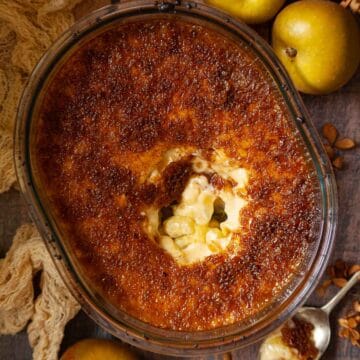 Close-up of a part-served Malvern pudding with custard and apples.