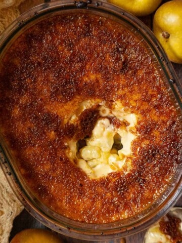 Close-up of a part-served Malvern pudding with custard and apples.