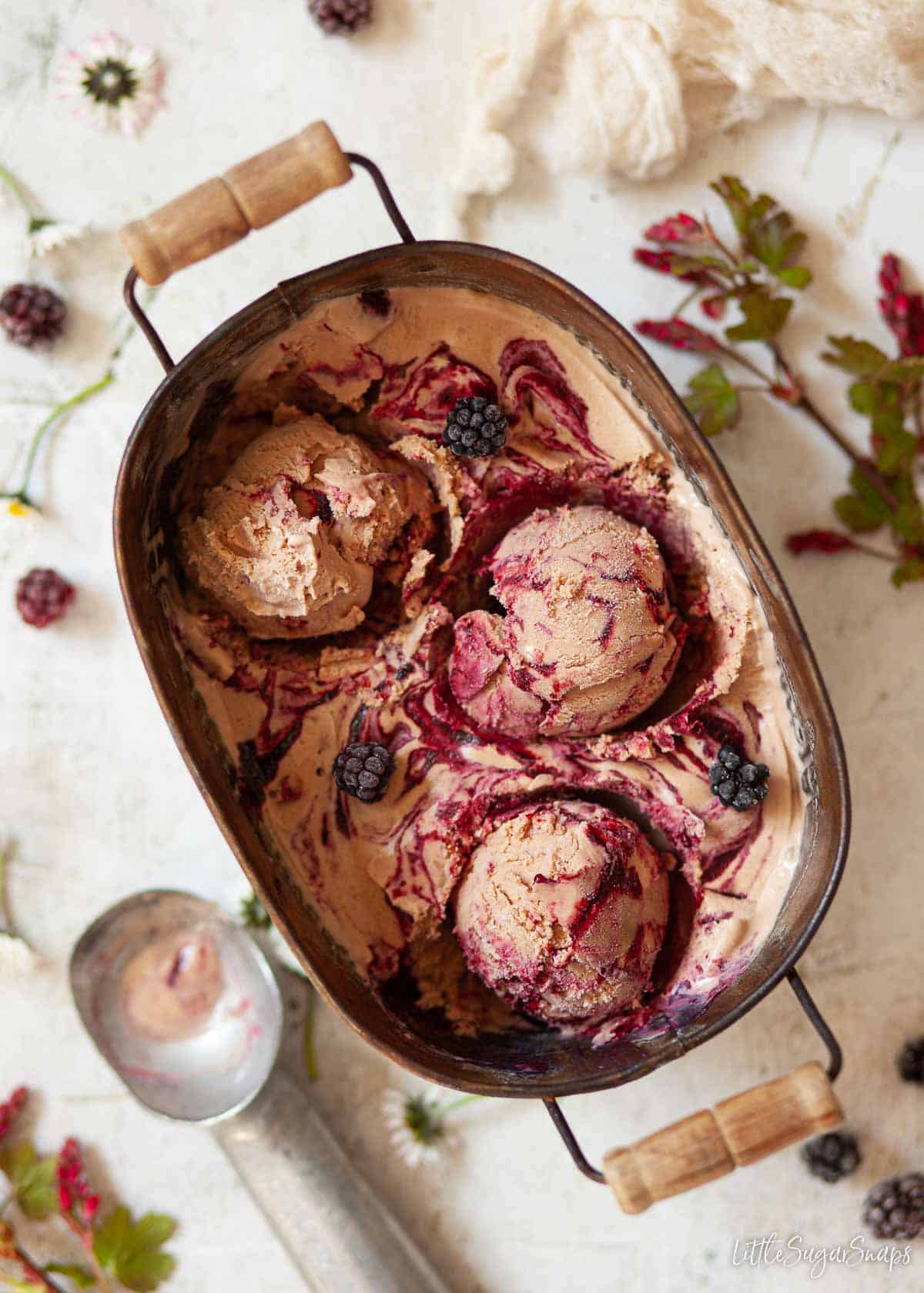 A tin of Nutella ice cream with blackberry fruit ripple. Balls have been scooped out.