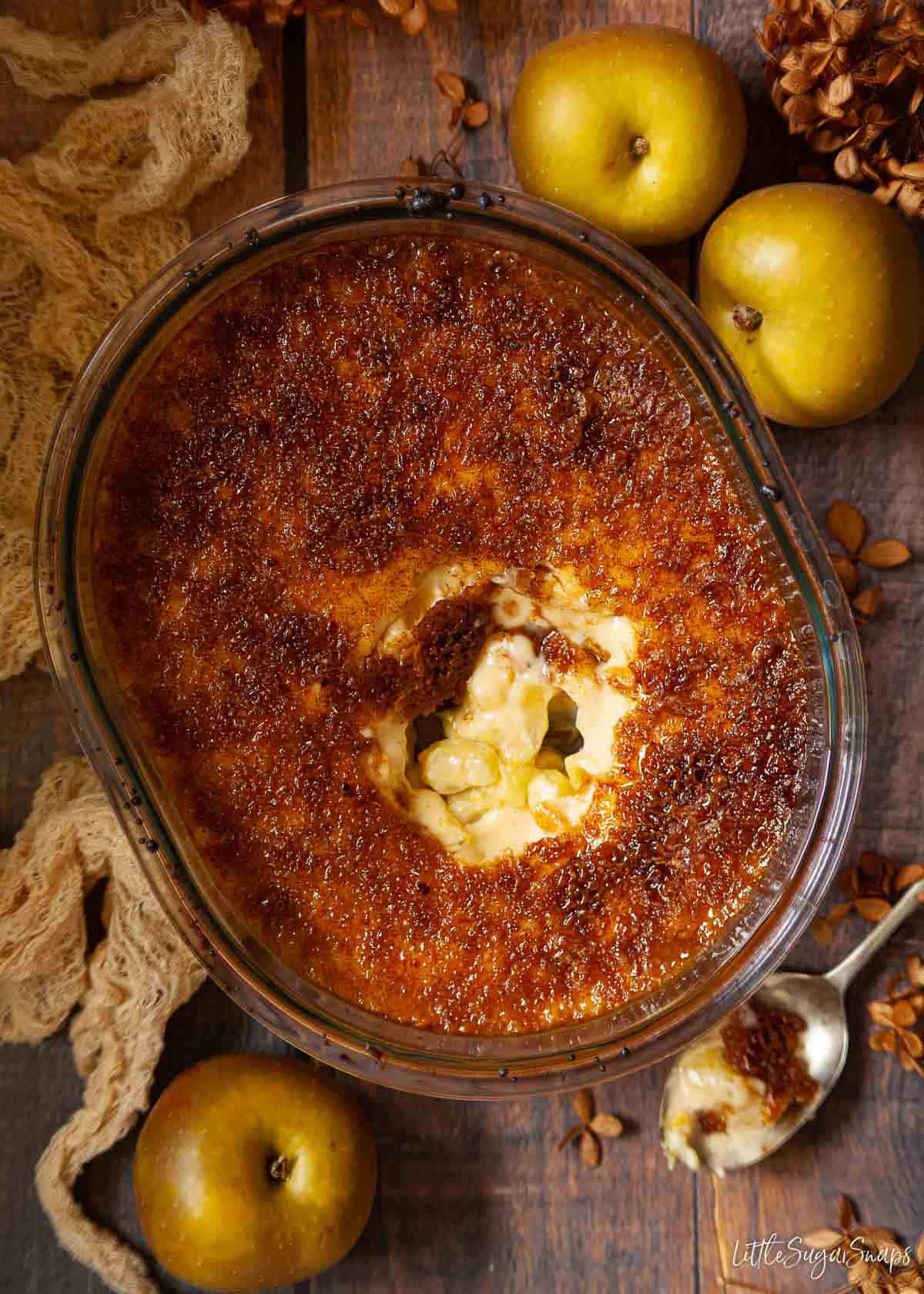 A Malvern apple pudding part served revealing apples underneath custard.