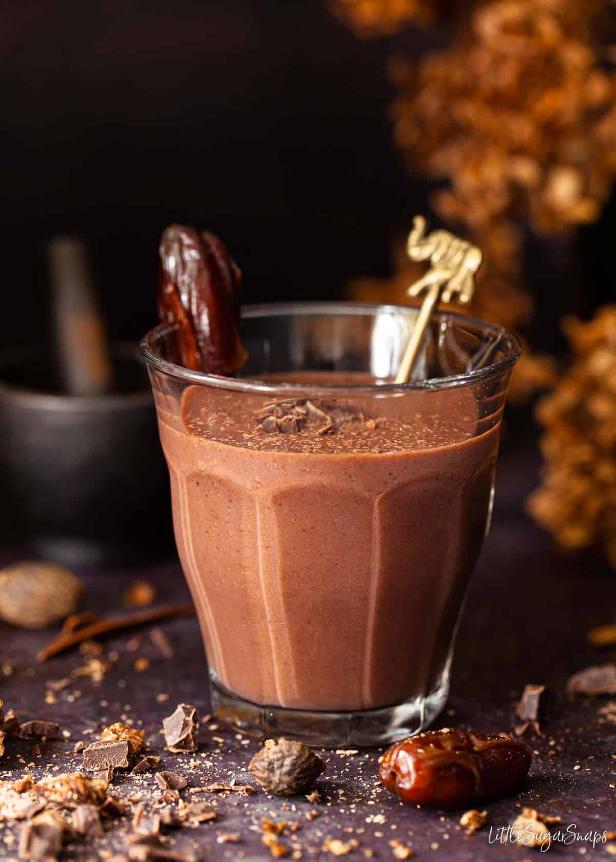 A chocolate date shake milkshake garnished with a Deglet Noor date and chocolate shavings